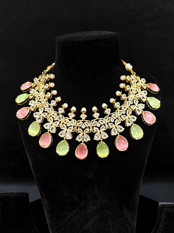 Close-up of an ornate traditional (Gold Polish) Pink & Green Collar jewellery set and earrings with Diamond Polki, Monalisa Stone and Colored Stones. Wedding guest wearing a sparkling American diamond necklace with a saree. A graceful woman wearing a trending American diamond necklace for a 2026 wedding celebration.