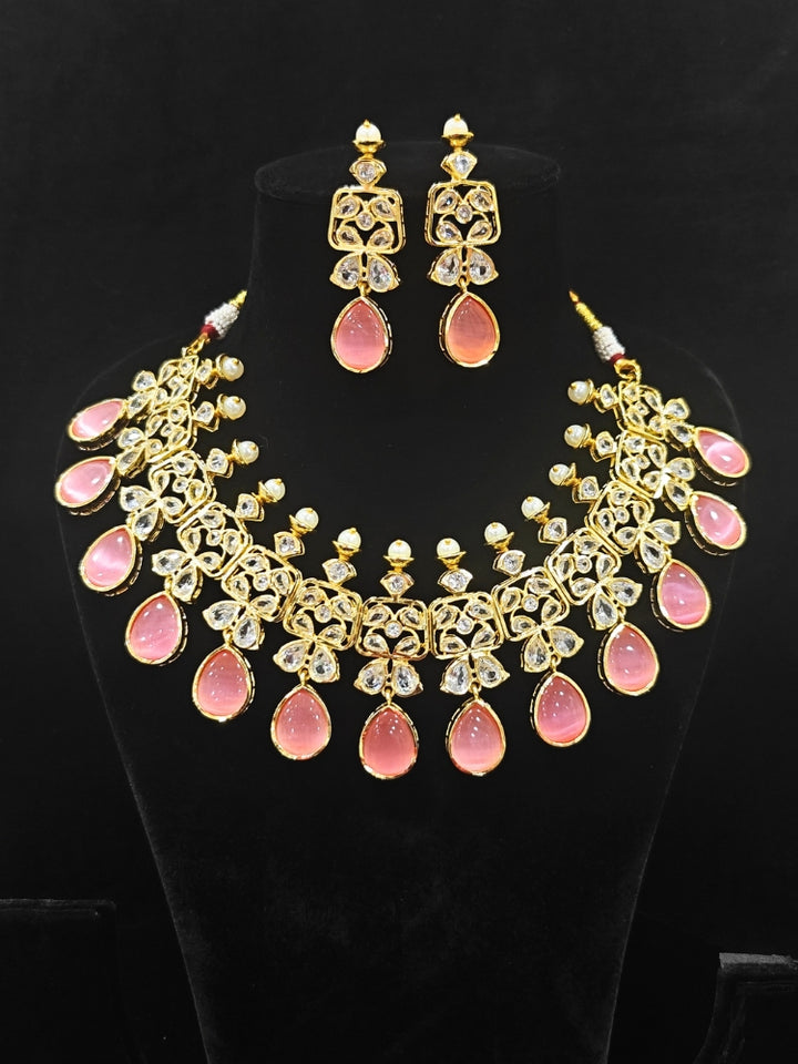 Close-up of an ornate traditional (Gold Polish) Pink Collar jewellery set and earrings with Diamond Polki, Monalisa Stone and Colored Stones. Wedding guest wearing a sparkling American diamond necklace with a saree. A graceful woman wearing a trending American diamond necklace for a 2026 wedding celebration.