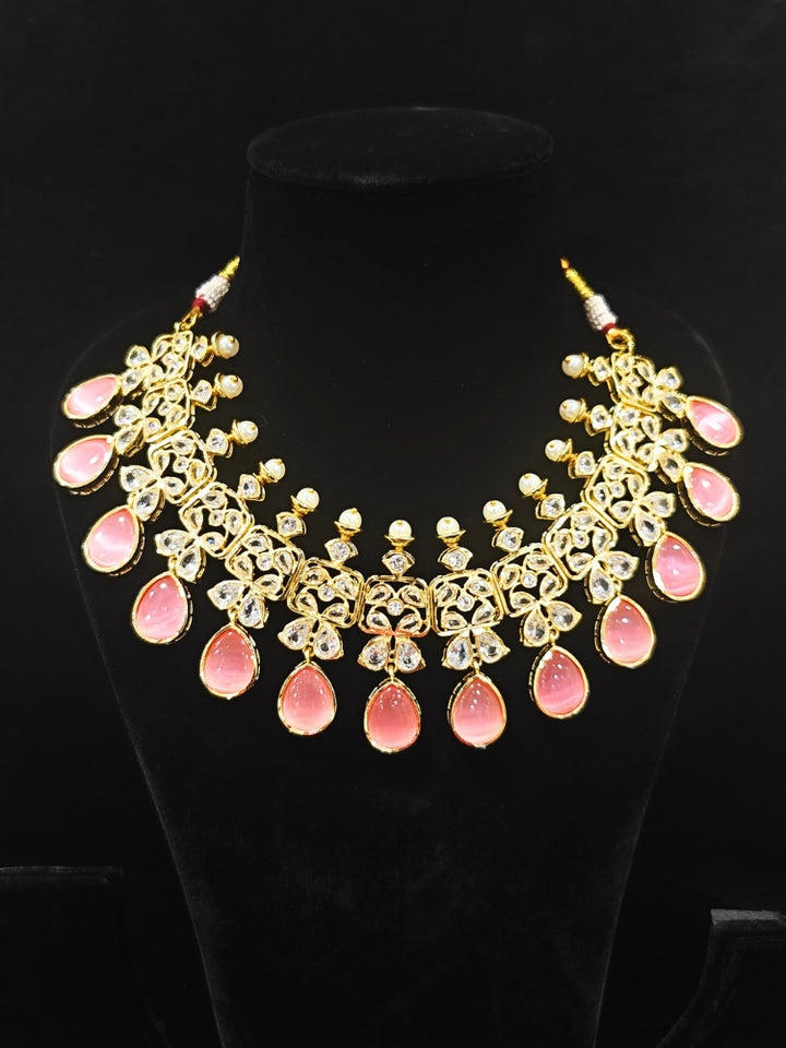 Close-up of an ornate traditional (Gold Polish) Pink Collar jewellery set and earrings with Diamond Polki, Monalisa Stone and Colored Stones. Wedding guest wearing a sparkling American diamond necklace with a saree. A graceful woman wearing a trending American diamond necklace for a 2026 wedding celebration.