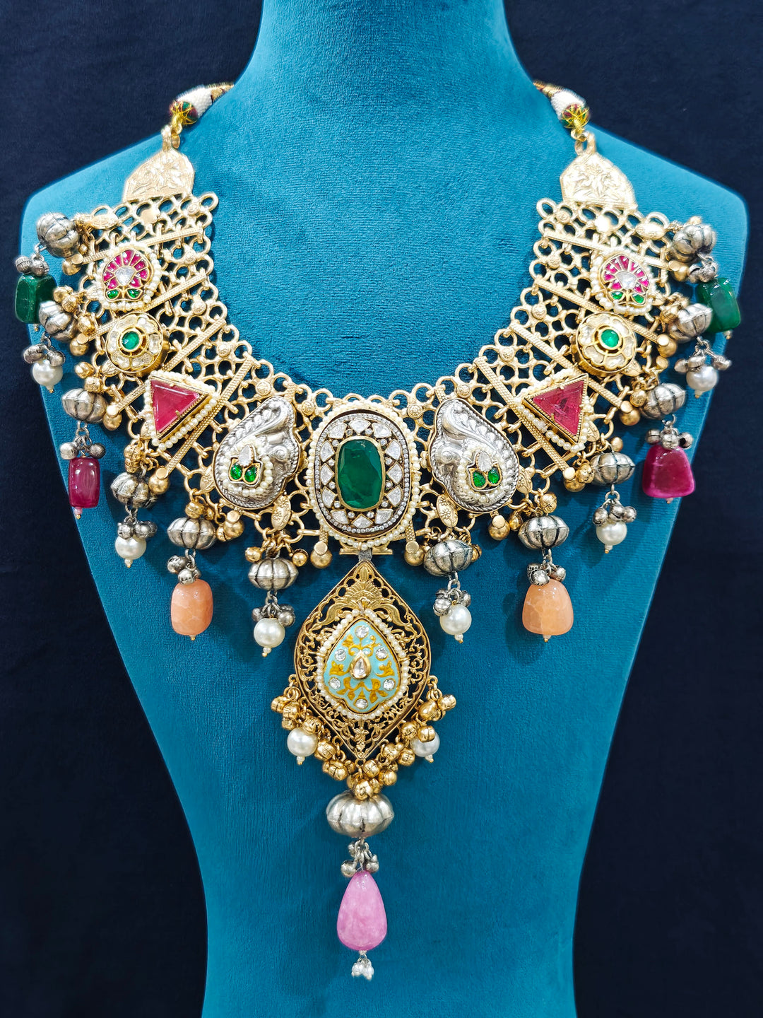 Close-up of an ornate traditional KASHMIRI-BOHO Meenakari Green and Ruby Pink gold Collar jewellery set and earrings with Pachi Kundan, Silver Balls, Pearls, Doublet Stones, Tumble Stone, Ghungroo and Meenakari. Festive celebration look enhanced with traditional Meenakari jewelry. 