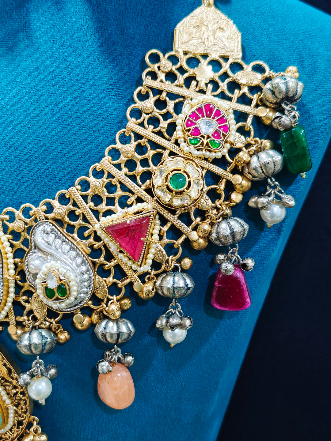 Close-up of an ornate traditional KASHMIRI-BOHO Meenakari Green and Ruby Pink gold Collar jewellery set and earrings with Pachi Kundan, Silver Balls, Pearls, Doublet Stones, Tumble Stone, Ghungroo and Meenakari. Festive celebration look enhanced with traditional Meenakari jewelry. 