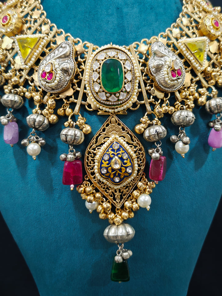 Close-up of an ornate traditional KASHMIRI-BOHO Meenakari Green & Yellow gold Collar jewellery set and earrings with Pachi Kundan, Silver Balls, Pearls, Doublet Stones, Tumble Stone, Ghungroo and Meenakari. Festive celebration look enhanced with traditional Meenakari jewelry. 
