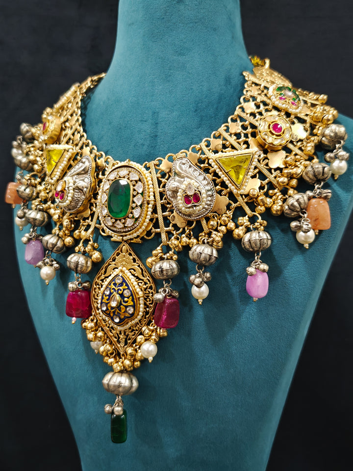 Close-up of an ornate traditional KASHMIRI-BOHO Meenakari Green & Yellow gold Collar jewellery set and earrings with Pachi Kundan, Silver Balls, Pearls, Doublet Stones, Tumble Stone, Ghungroo and Meenakari. Festive celebration look enhanced with traditional Meenakari jewelry. 