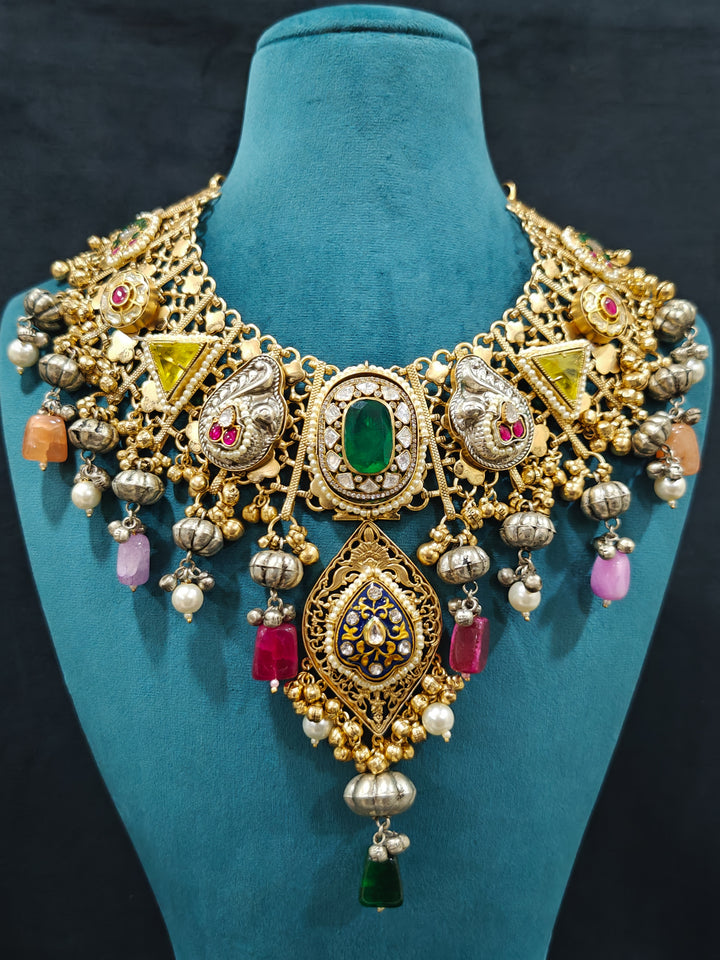 Close-up of an ornate traditional KASHMIRI-BOHO Meenakari Green & Yellow gold Collar jewellery set and earrings with Pachi Kundan, Silver Balls, Pearls, Doublet Stones, Tumble Stone, Ghungroo and Meenakari. Festive celebration look enhanced with traditional Meenakari jewelry. 