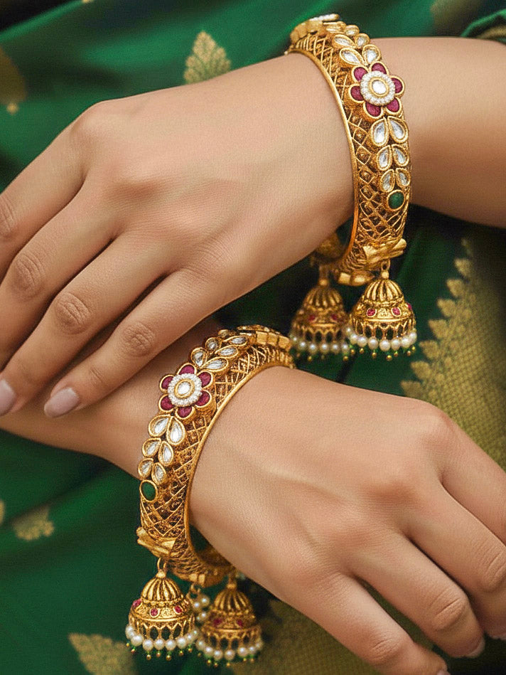 Close-up of a woman wearing an ornate traditional Rajwadi gold Bangle with Filigree Work, Pearls, Pink & Green and Colored Stone. Bridal mehendi outfit styled with luxury artificial Rajwadi bangles. Woman wearing bridal artificial Rajwadi bangles for a grand celebration.