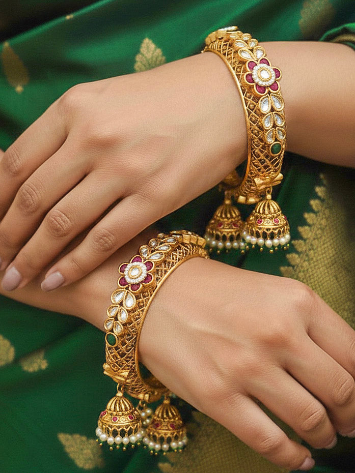 Close-up of a woman wearing an ornate traditional Rajwadi gold Bangle with Filigree Work, Pearls, Pink & Green and Colored Stone. Bridal mehendi outfit styled with luxury artificial Rajwadi bangles. Woman wearing bridal artificial Rajwadi bangles for a grand celebration.