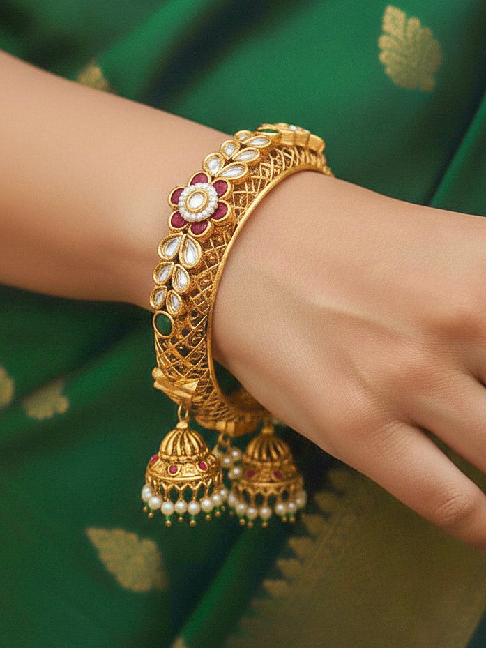 Close-up of a woman wearing an ornate traditional Rajwadi gold Bangle with Filigree Work, Pearls, Pink & Green and Colored Stone. Bridal mehendi outfit styled with luxury artificial Rajwadi bangles. Woman wearing bridal artificial Rajwadi bangles for a grand celebration.