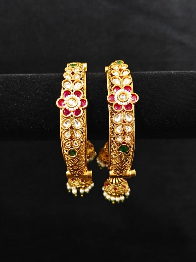 Close-up of an ornate traditional Rajwadi gold Bangle with Filigree Work, Pearls, Pink & Green and Colored Stone. Reception party outfit styled with premium wedding Rajwadi bangles. Close-up of high-quality imitation Rajwadi bangles. Perfect Rajwadi Bangles for weddings and festivals.