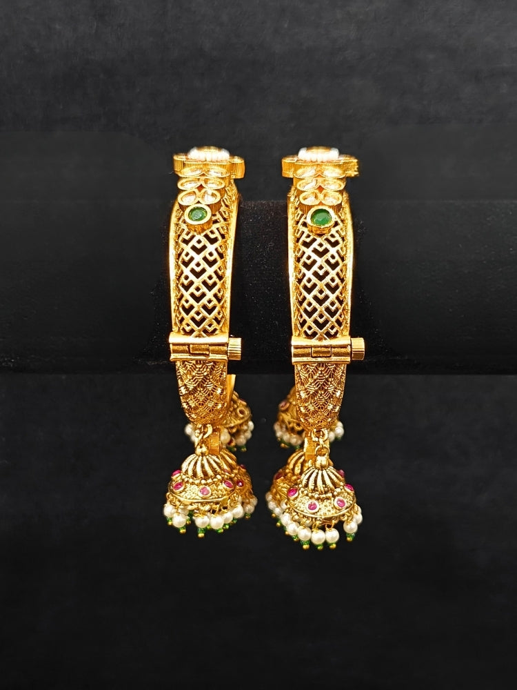 Close-up of an ornate traditional Rajwadi gold Bangle with Filigree Work, Pearls, Pink & Green and Colored Stone. Reception party outfit styled with premium wedding Rajwadi bangles. Close-up of high-quality imitation Rajwadi bangles. Perfect Rajwadi Bangles for weddings and festivals.
