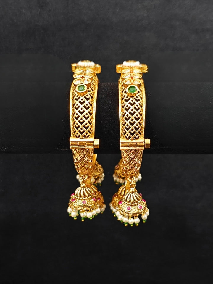 Close-up of an ornate traditional Rajwadi gold Bangle with Filigree Work, Pearls, Pink & Green and Colored Stone. Reception party outfit styled with premium wedding Rajwadi bangles. Close-up of high-quality imitation Rajwadi bangles. Perfect Rajwadi Bangles for weddings and festivals.
