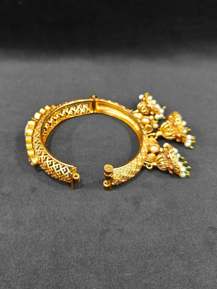 Close-up of an ornate traditional Rajwadi gold Bangle with Filigree Work, Pearls, Pink & Green and Colored Stone. Reception party outfit styled with premium wedding Rajwadi bangles. Close-up of high-quality imitation Rajwadi bangles. Perfect Rajwadi Bangles for weddings and festivals.