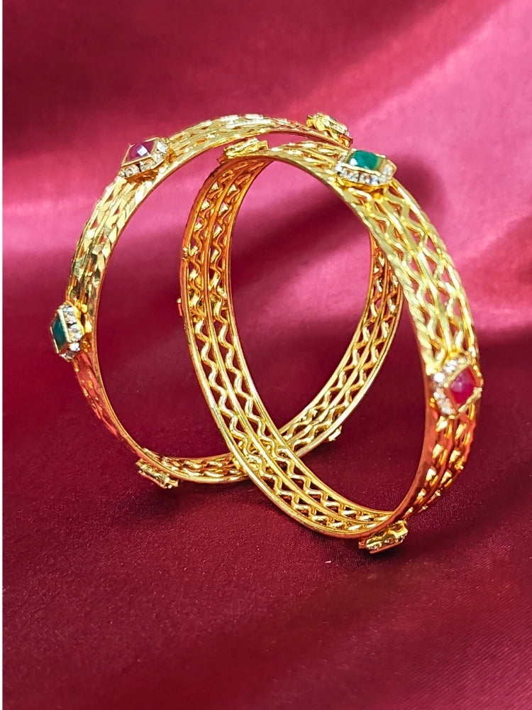 Close-up of an ornate traditional (Gold Polish) Bangles Set with American Diamond and Pink & Green Colored Stones. Woman stacking artificial Colored Stone bangles for a festive Diwali celebration. Festive Navratri outfit paired with stacked imitation Colored Stone bangles.