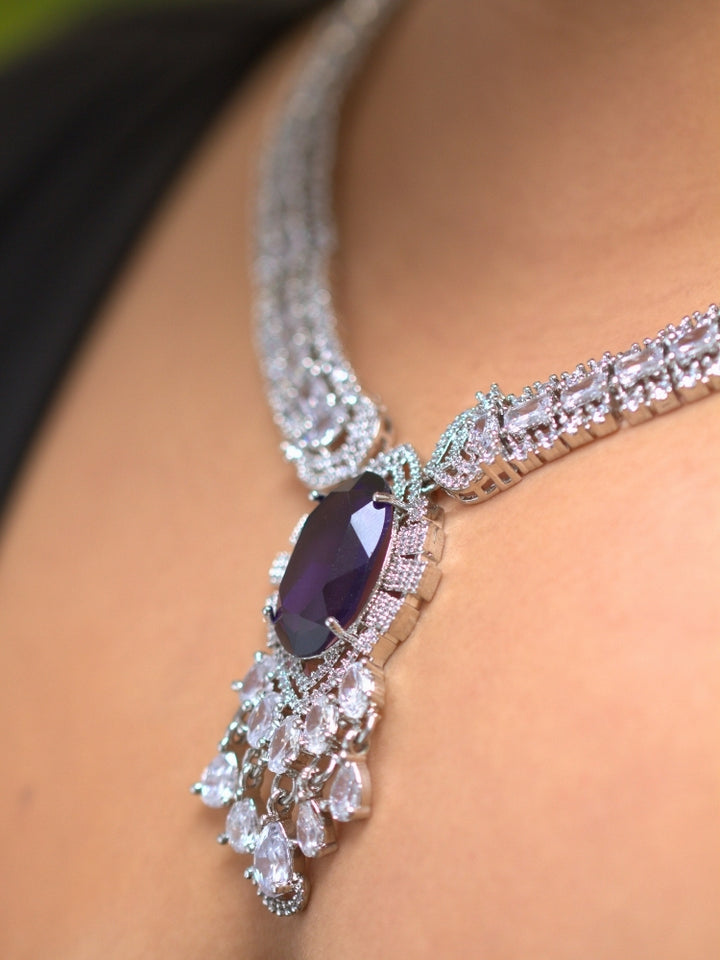 A beautiful woman wearing an elegant artificial diamond necklace with purple colored stone and matching earrings. This premium artificial diamond jewelry set is perfect for special occasions, from Indian weddings to engagement parties, offering sophisticated glamour without the high price tag.