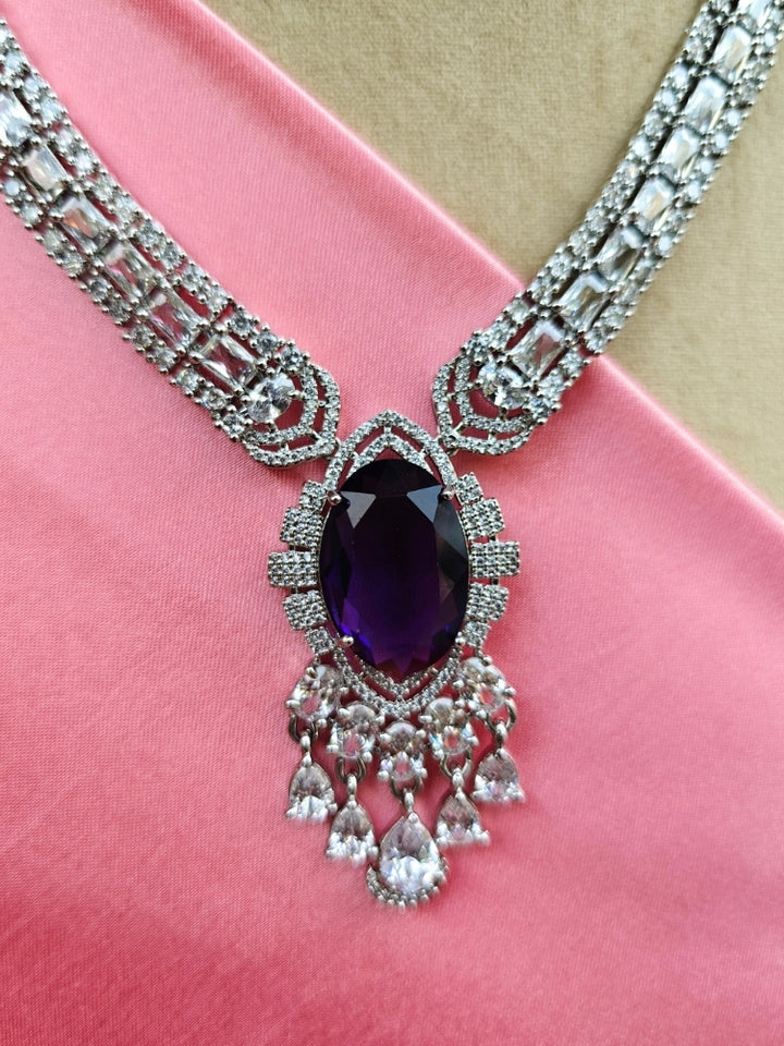 Close-up of a luxurious artificial diamond jewelry featuring a designer diamond necklace with purple colored stone and earrings set, crafted for bridal fashion and high-end weddings. This beautiful diamond jewelry set offers the brilliance of real diamonds at an affordable price.