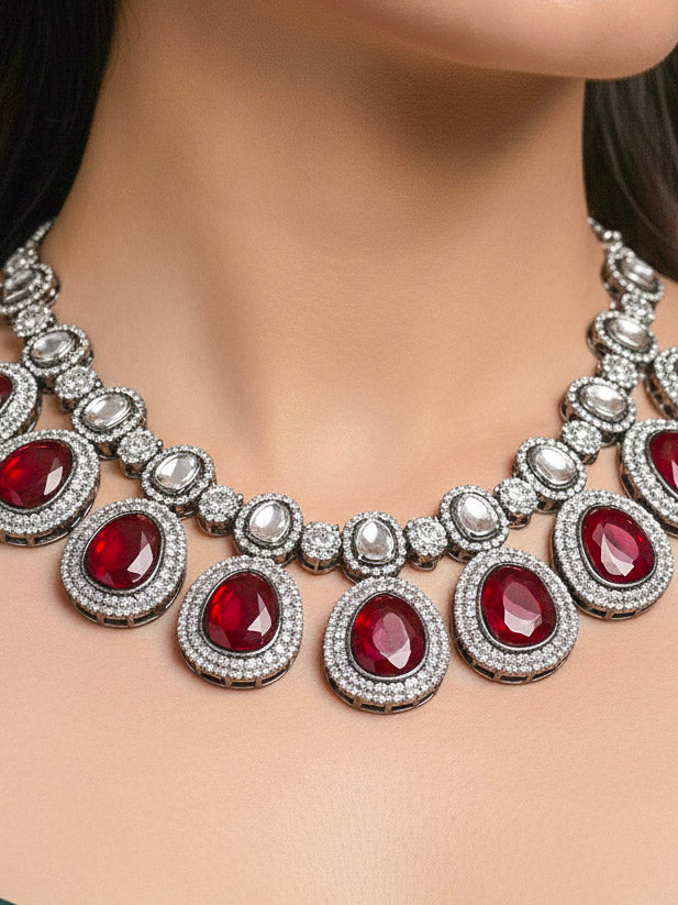 Close-up of a woman wearing an ornate Indo-western American Diamond Red Collar jewellery set and earrings with American Diamonds and Monalisa Stones. Woman styling a statement American diamond necklace with an off-shoulder gown for a reception. Close-up of a luxury American Diamond imitation necklace styled.