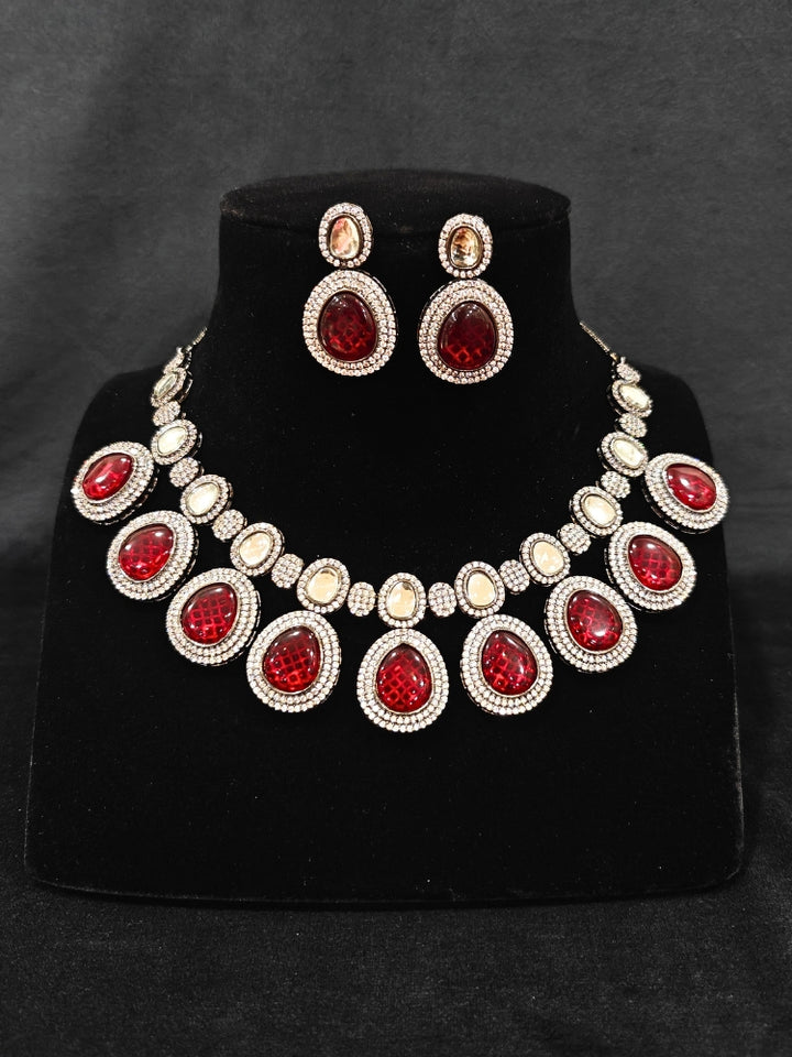 Close-up of an ornate Indo-western American Diamond Red Collar jewellery set and earrings with American Diamonds and Monalisa Stones. Woman styling a statement American diamond necklace with an off-shoulder gown for a reception. Close-up of a luxury American Diamond imitation necklace styled.