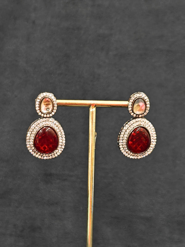 Close-up of an ornate Indo-western American Diamond Red Collar jewellery set and earrings with American Diamonds and Monalisa Stones. Woman styling a statement American diamond necklace with an off-shoulder gown for a reception. Close-up of a luxury American Diamond imitation necklace styled.