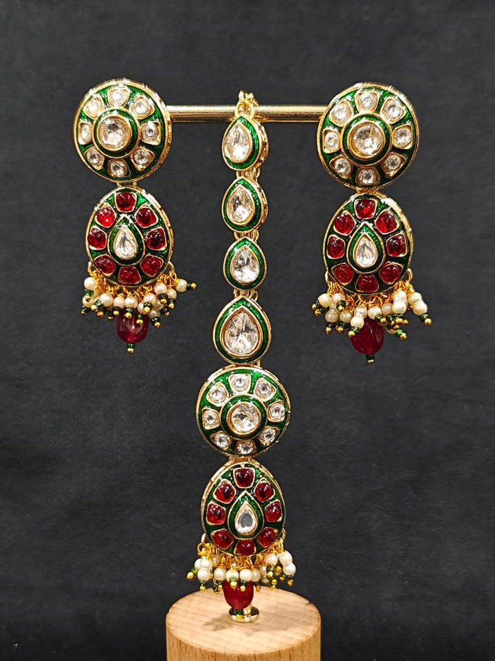 Close-up of an ornate traditional Red Jewelry Set, Earrings and Mangtikka with Kundan and Colored Stones. Bride wearing a traditional Kundan artificial necklace set for her wedding ceremony. A trending Kundan artificial jewelry for wedding season in India.