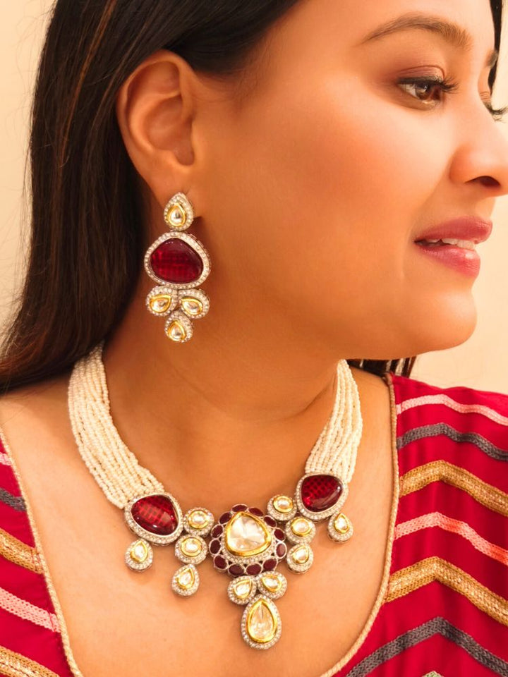 A woman in a Red embroidered outfit smiles, showcasing the Peacoski Red Tamanna Necklace Set and matching earrings. Her soft makeup highlights the elegance of this statement jewelry ensemble.