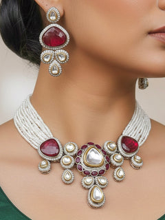 Close-up of a woman wearing an ornate traditional Red Collar Kundan jewellery set and earrings with American diamonds, Monalisa stone, Pearls, Kundan and Colored Stones. Festive Diwali outfit paired with a premium Kundan jewelry piece. Woman wearing trending Kundan artificial jewelry for wedding season in India.