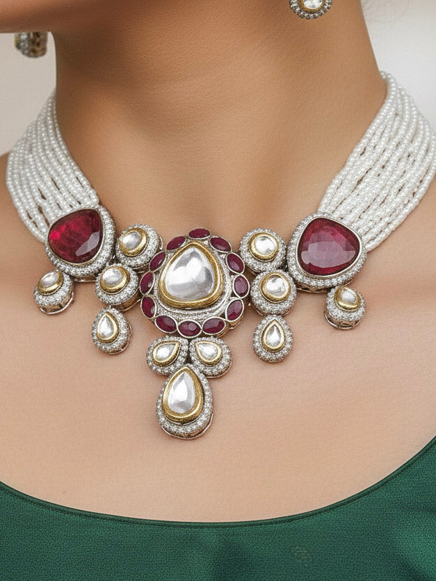 Close-up of a woman wearing an ornate traditional Red Collar Kundan jewellery set and earrings with American diamonds, Monalisa stone, Pearls, Kundan and Colored Stones. Festive Diwali outfit paired with a premium Kundan jewelry piece. Woman wearing trending Kundan artificial jewelry for wedding season in India.