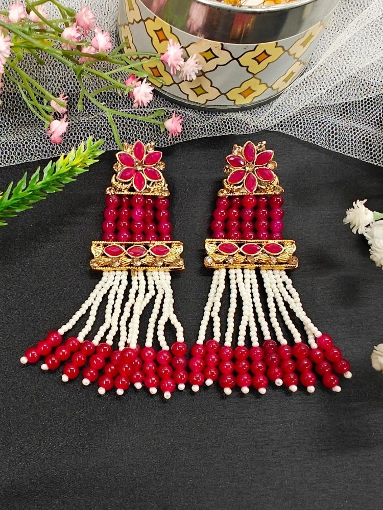 The Red Tripti Earrings are ornate gold earrings adorned with white pearls and crystal stones. Featuring long dangling pearl strands, they’re perfect for pairing with a wedding ceremony dress.