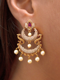 Close-up of a woman wearing an ornate traditional (gold Polish) Red Diamond  Earrings with American Diamond and Pearls. A woman wearing a luxury American diamond Earrings styled beautifully for a wedding guest look in India. Festive Diwali outfit styled with an American diamond artificial Earrings.