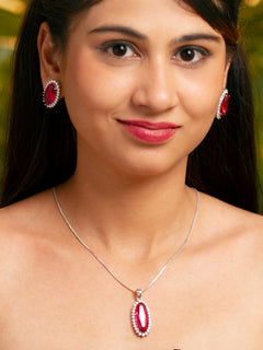 Close-up of a woman wearing an ornate Western (Silver Polish) Red Pendant set and Earrings with American Diamond and Red Colored Stone. Close-up of a cocktail party look featuring a premium Colored Stone Pendant Set. Party wear outfit completed with a lightweight Colored Stone Pendant set.