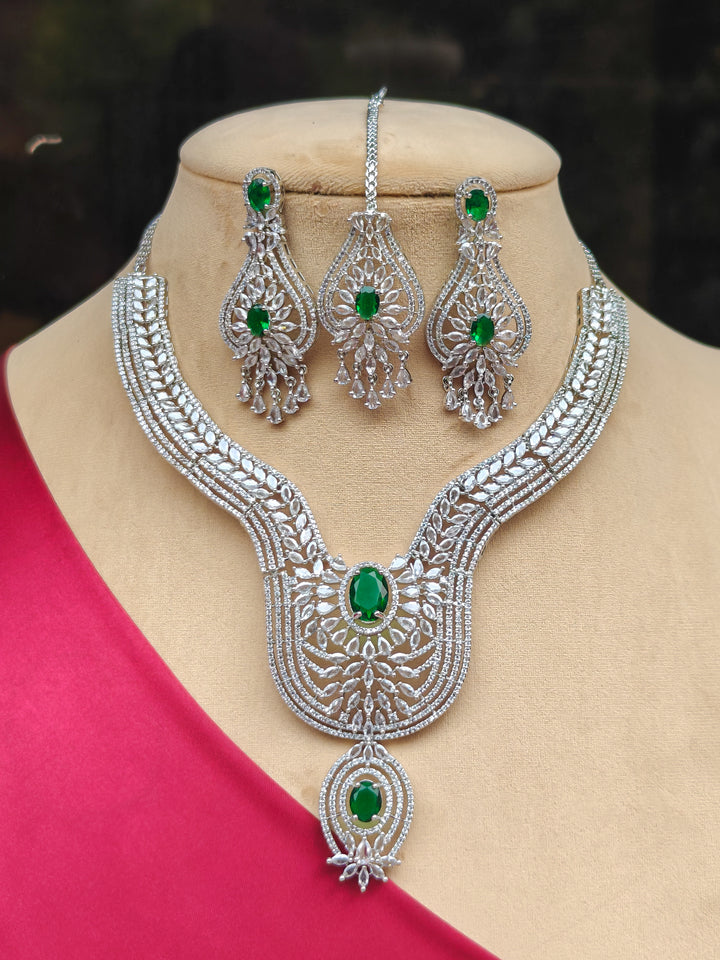 "A woman showcasing a beautiful artificial diamond and green colored stone necklace and earrings and maangtikka  set, ideal for festivals, family gatherings, and special celebrations in India. This elegant diamond jewelry provides the perfect blend of sparkle and tradition, with a modern twist."
