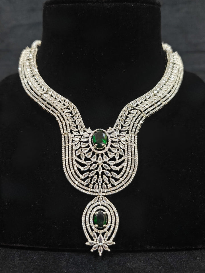 Close-up of an ornate Western Silver Diamond Collar jewellery set, earrings and Mangtikka with American Diamond and Green Color Stone. Bride-to-be styled in a premium American diamond artificial necklace for her reception party.
Close-up of a cocktail party look featuring a premium American diamond necklace.