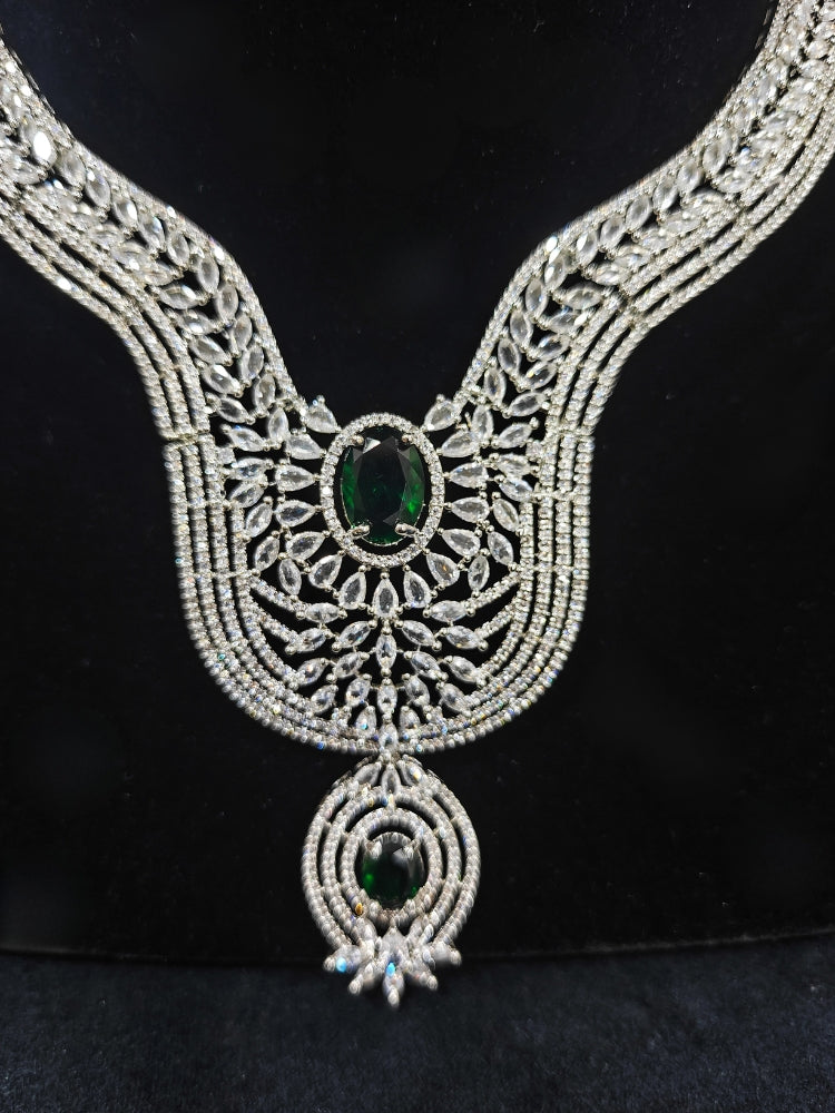 Close-up of an ornate Western Silver Diamond Collar jewellery set, earrings and Mangtikka with American Diamond and Green Color Stone. Bride-to-be styled in a premium American diamond artificial necklace for her reception party.
Close-up of a cocktail party look featuring a premium American diamond necklace.