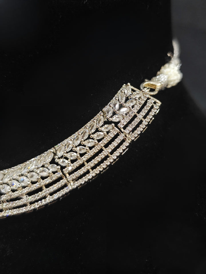 Close-up of an ornate Western Silver Diamond Collar jewellery set, earrings and Mangtikka with American Diamond and Green Color Stone. Bride-to-be styled in a premium American diamond artificial necklace for her reception party.
Close-up of a cocktail party look featuring a premium American diamond necklace.