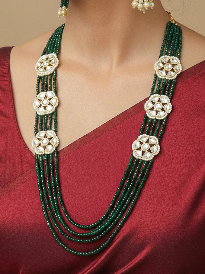 Close-up of a woman wearing an ornate traditional Green Long jewellery set and earrings with Crystal Beads, Kundan and Pearls. Mehendi ceremony look completed with a handcrafted Kundan jewelry set. Festive saree styling with a premium artificial Kundan necklace.