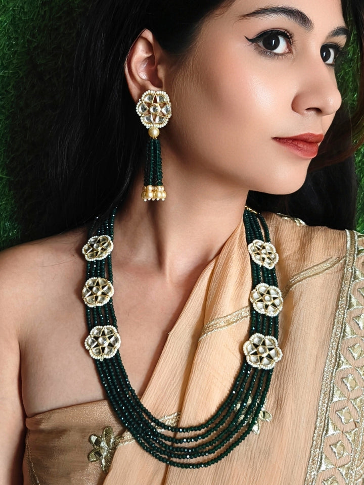 Close-up of a woman wearing an ornate traditional Green Long jewellery set and earrings with Crystal Beads, Kundan and Pearls. Mehendi ceremony look completed with a handcrafted Kundan jewelry set. Festive saree styling with a premium artificial Kundan necklace.