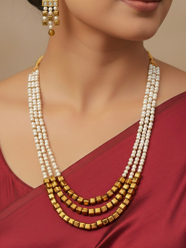 Close-up of a woman wearing an ornate Indo-Western White and Gold Pearl Layered Jewellery set and Earring with Pearls and American Diamond. Festive celebration look enhanced with traditional Pearl jewelry. Close-up of enamel work in Meenakari artificial Pearl jewelry.