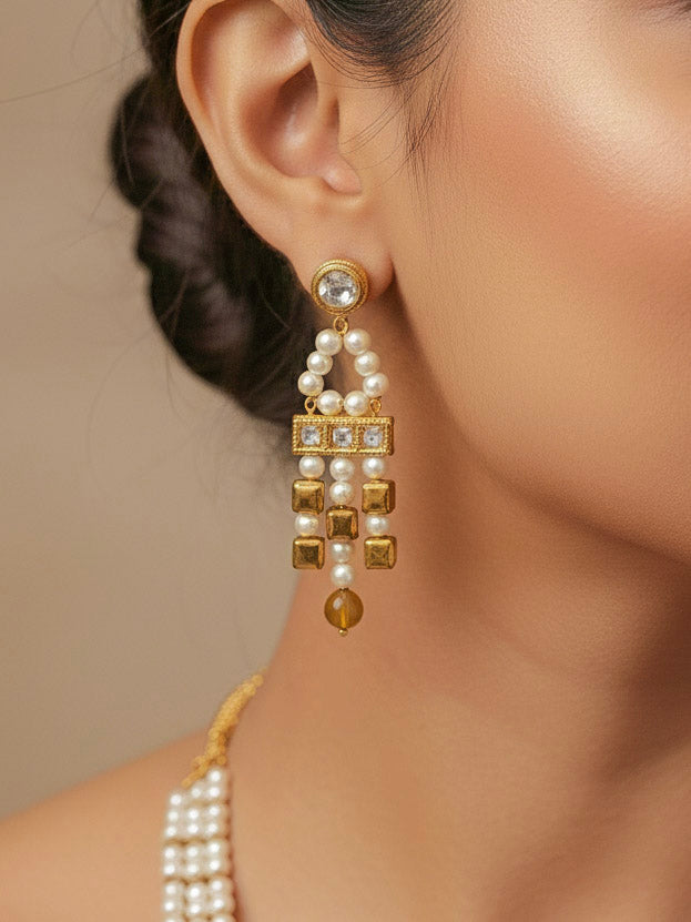 Close-up of a woman wearing an ornate Indo-Western White and Gold Pearl Layered Jewellery set and Earring with Pearls and American Diamond. Festive celebration look enhanced with traditional Pearl jewelry. Close-up of enamel work in Meenakari artificial Pearl jewelry.