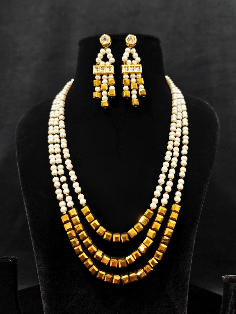 Close-up of an ornate Indo-Western White and Gold Pearl Layered Jewellery set and Earring with Pearls and American Diamond. Festive celebration look enhanced with traditional Pearl jewelry. Close-up of enamel work in Meenakari artificial Pearl jewelry.