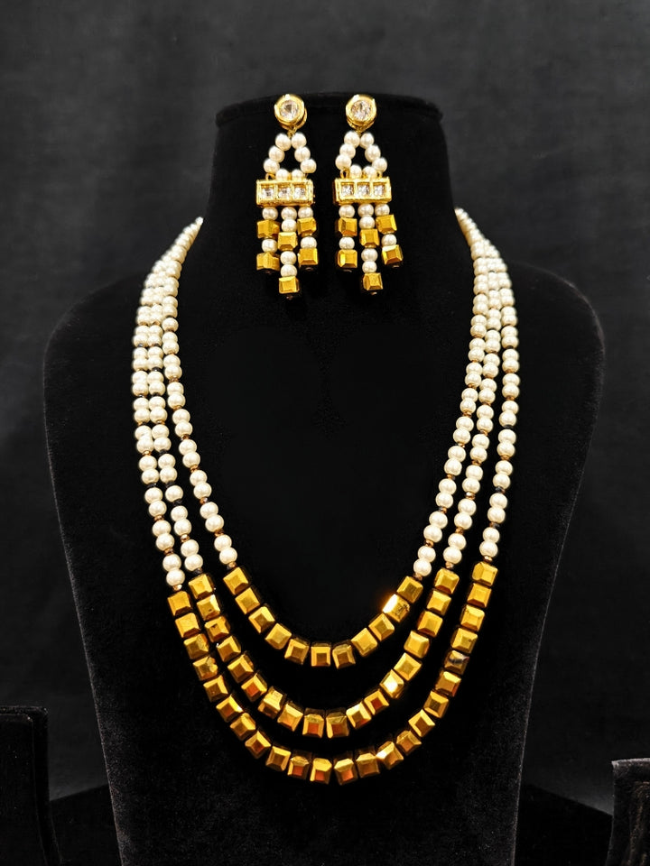 Close-up of an ornate Indo-Western White and Gold Pearl Layered Jewellery set and Earring with Pearls and American Diamond. Festive celebration look enhanced with traditional Pearl jewelry. Close-up of enamel work in Meenakari artificial Pearl jewelry.