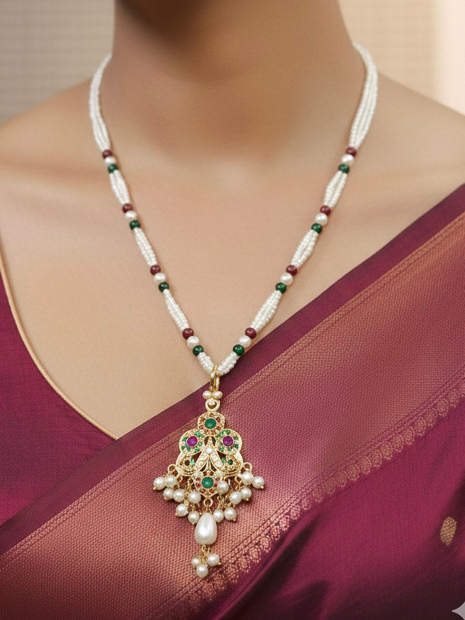 Close-up of a woman wearing an ornate traditional (Gold Polish) Multi-Color Pendant Set and Earrings with  Pearl and Colored Stones. Festive saree look completed with a handcrafted Jadau Pendant. Close-up of high-quality Jadau artificial Pendant craftsmanship.