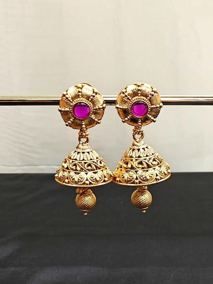 Close-up of an ornate traditional (Gold Polish) Earrings set with Pink Colored Stone in middle. Saree look completed with an elegant Colored Stone artificial jewelry piece. Woman wearing trending Colored Stone artificial jewelry for wedding season in India.