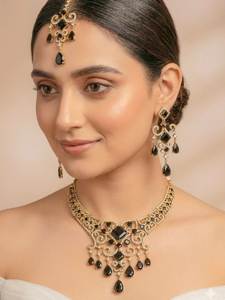 "A bride-to-be wearing an exquisite artificial diamond necklace with black colored stone and matching earrings with maangtikka, designed for the perfect engagement look. This stunning artificial diamond jewelry set offers luxury and sophistication while being an affordable alternative to natural diamonds."
