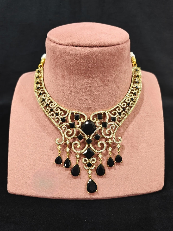 A glamorous artificial diamond necklace with black colored stone paired with chic earrings and maangtikka, perfect for bridal wear. This high-quality artificial diamond jewelry set is the ideal choice for modern brides looking for a budget-friendly option with timeless sparkle."