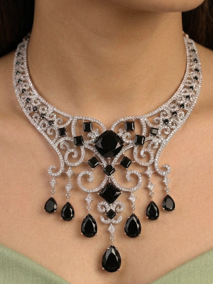 Close-up of a woman wearing an ornate Black Indo-Western Diamond Silver Collar jewellery set and earrings and maangtikka with American Diamond and Black Colored Stones. Bride-to-be styled in a premium American diamond artificial necklace for her reception party. Elegant wedding jewelry look featuring a premium artificial American diamond necklace.