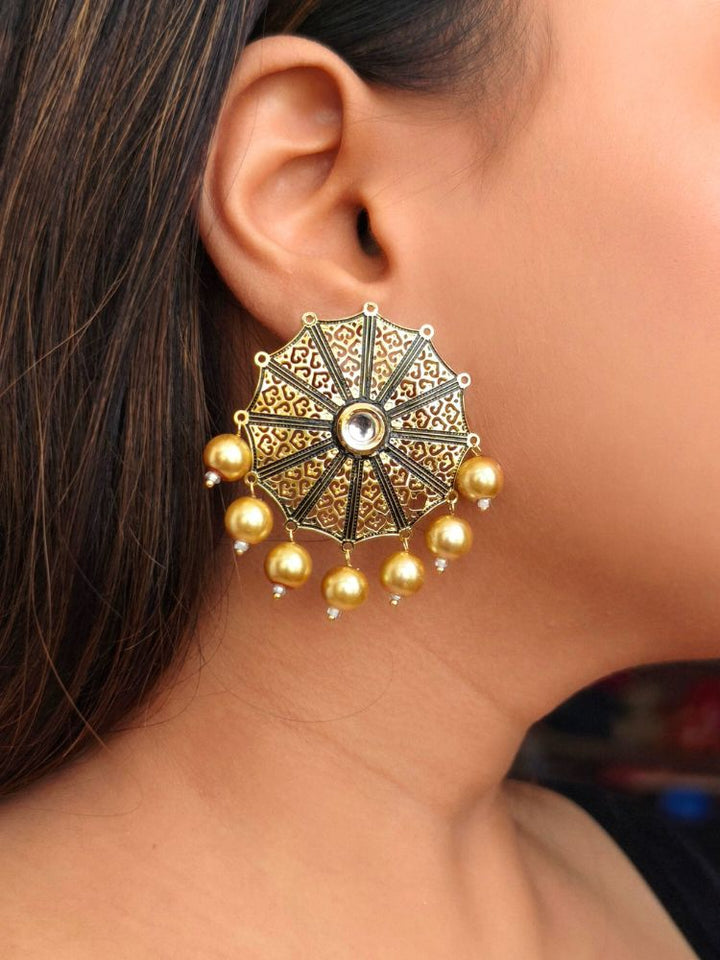 A close-up of a woman’s ear adorned with the Roshni Earrings—large, ornate gold earrings featuring intricate filigree design, dangling Pearls. The circular design covers most of her earlobe, perfect for wedding ceremony attire.