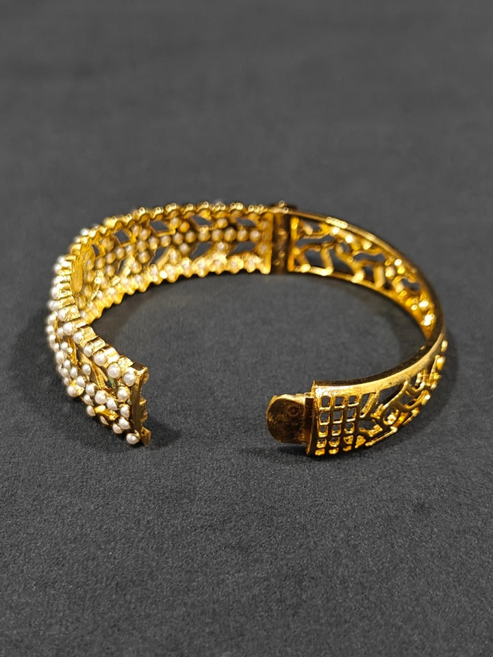 Close-up of an ornate traditional White jadau gold Bracelet with matched Ring with pearls. Festive outfit paired with a premium imitation Jadau bracelet with Ring in India. Close-up of a high-quality imitation Jadau bracelet with Ring for festive wear.