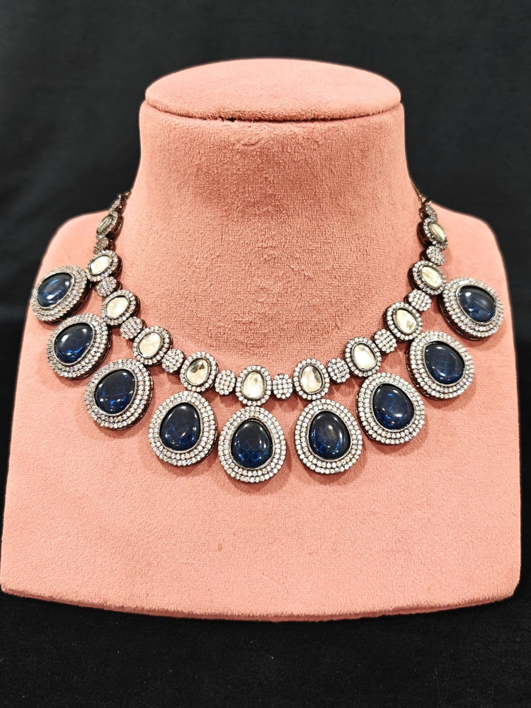 Close-up of an ornate Indo-western American Diamond Royal Blue Collar jewellery set and earrings with American Diamonds and Monalisa Stones. Woman styling a statement American diamond necklace with an off-shoulder gown for a reception. Close-up of a luxury American Diamond imitation necklace styled.