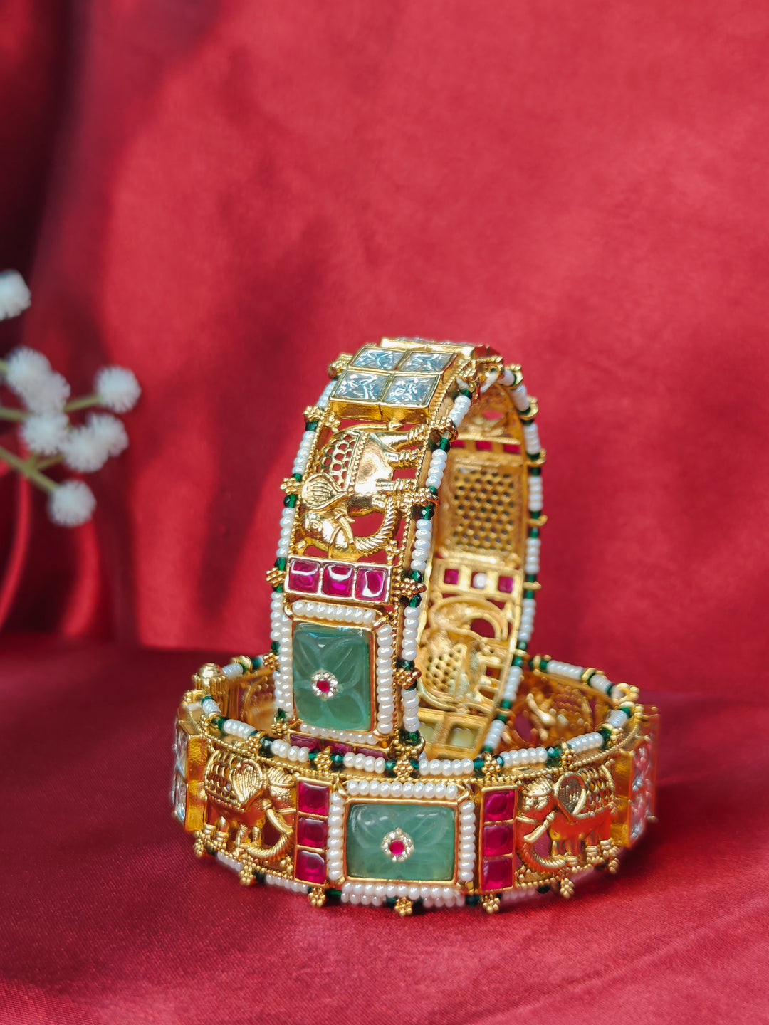 Close-up of an ornate traditional (Gold Polish) Mint Green Bangles set with Colored Stones, Pearl and Polki. Woman stacking artificial Colored Stone bangles for a festive Diwali celebration. Saree styling inspiration featuring traditional imitation Colored Stone bangles.