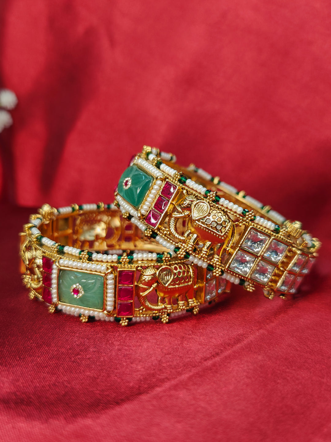 Close-up of an ornate traditional (Gold Polish) Mint Green Bangles set with Colored Stones, Pearl and Polki. Woman stacking artificial Colored Stone bangles for a festive Diwali celebration. Saree styling inspiration featuring traditional imitation Colored Stone bangles.