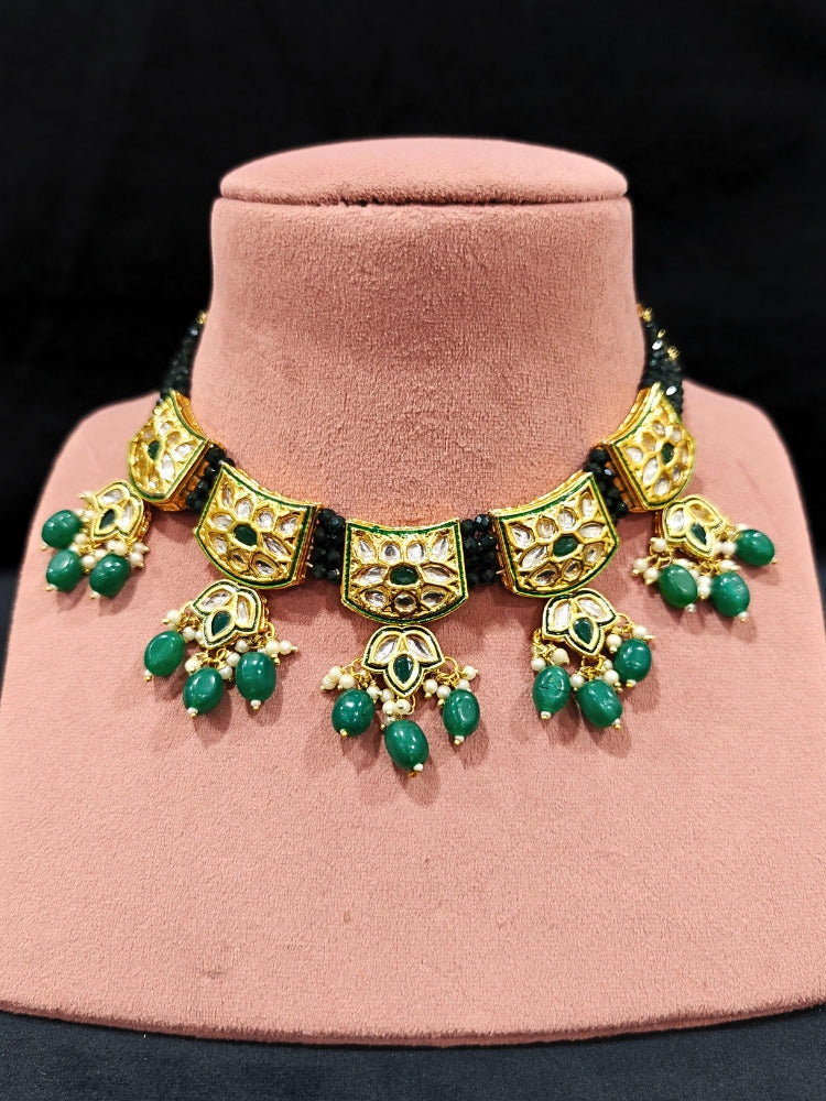 Close-up of an ornate traditional (Gold Polish) Dark Green Choker jewellery set and earrings with Pearl, Crystal stones, Kundan, Colored Stones and Tumble Beads. Mehendi ceremony look completed with a handcrafted Kundan jewelry set. Wedding celebration look enhanced with a statement Kundan necklace.