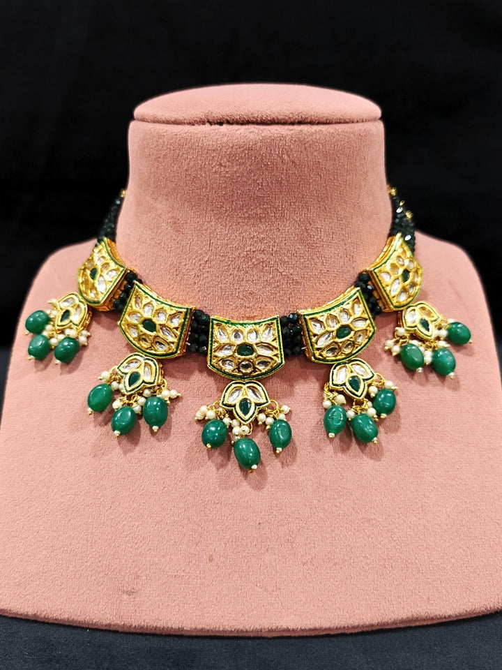 Close-up of an ornate traditional (Gold Polish) Dark Green Choker jewellery set and earrings with Pearl, Crystal stones, Kundan, Colored Stones and Tumble Beads. Mehendi ceremony look completed with a handcrafted Kundan jewelry set. Wedding celebration look enhanced with a statement Kundan necklace.